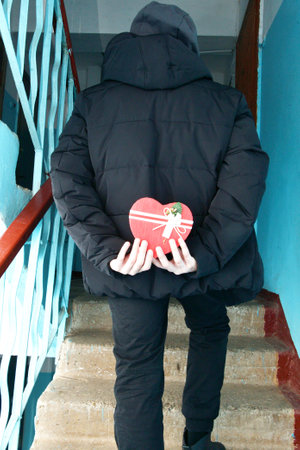 On Valentine's Day, a boy holds a gift behind his backの写真素材