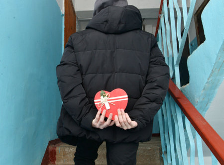 On Valentine's Day, a boy holds a gift behind his backの写真素材