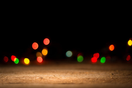 Colorful blurred lights in the dark background, wooden desk in front. Christmas background....
