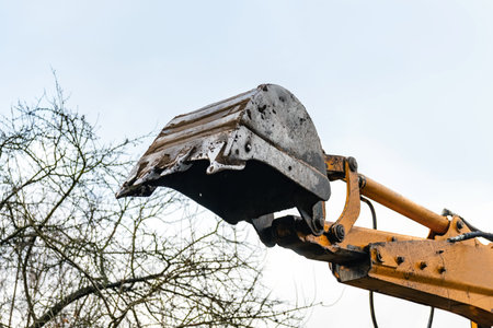 Excavator bucket on sky background, construction vehicles. Detail.