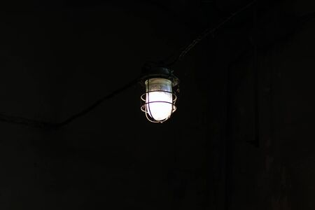 An old electric lamp dimly illuminates the communication tunnel. Close-up.の写真素材