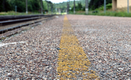 Yellow prohibition line extending to the horizon on a railway platform.