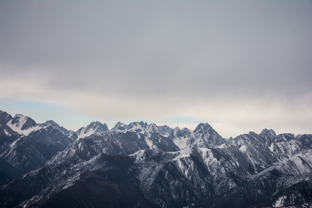 The tops of the mountains covered with snow. Mountains under the sky with clouds.の写真素材