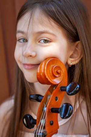 beautiful girl in a pink dress with a cello in the villageの写真素材