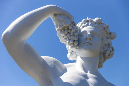 Russia. Vyborg. 06.30.2020. Statue of a man with grapes on a background of blue sky.のeditorial素材