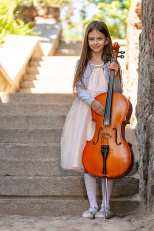 beautiful girl in a dress with a cello stands on the stepsの写真素材