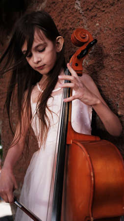beautiful girl in a pink dress stands with a celloの写真素材