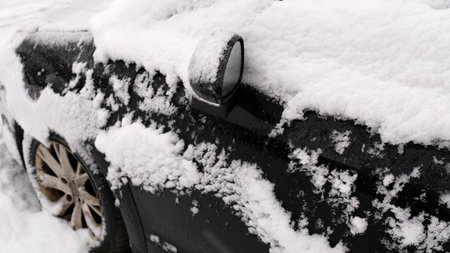 black car in the snow in the parking lot.