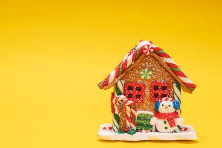 christmas house with a snowman on a yellow backgroundの写真素材