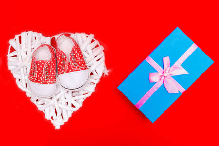 baby shoes with white polka dots on a red background with giftsの写真素材