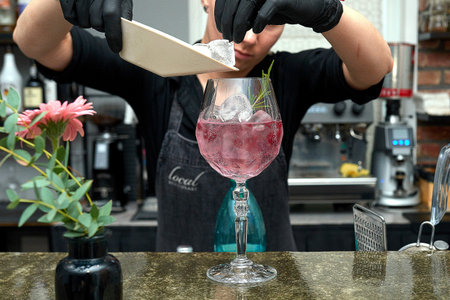 Bartender is preparing a delicious cocktail with ice at the counter