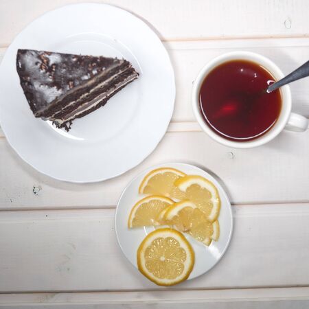chocolate cake slice with a white cup of tea and a handfulの写真素材