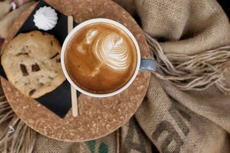 Coffee with froth and coffee beans in a sack on bagの写真素材