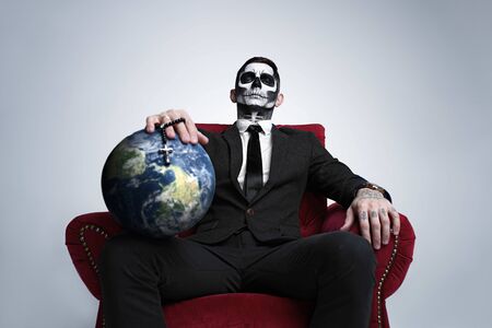 Death holds the planet earth in his hands. People die from coronavirus. Apocalypse doomsday, Satan destroys the world. The demon is terrifying.の写真素材