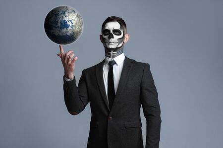 Death holds the planet earth in his hands. People die from coronavirus. Apocalypse doomsday, Satan destroys the world. The demon is terrifying.の写真素材