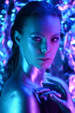 Fashion model woman in blue bright sparkles and neon lights posing in studio. Portrait of beautiful sexy woman. Art design colorful glitter glowing make upの写真素材