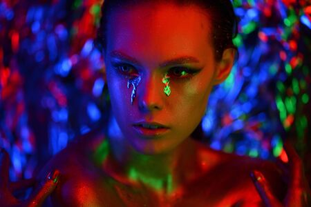 Fashion model metallic silver lips and face woman in neon uv red and purple lights, posing in studio, beautiful girl, glowing make-up, colorful make up.の写真素材