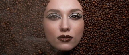 coffee beans around of face beautiful young womanの写真素材