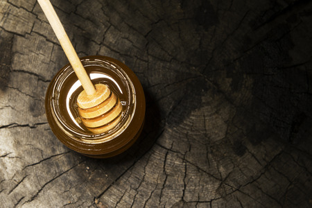 jar of honey and stick to honey on a wooden backgroundの写真素材
