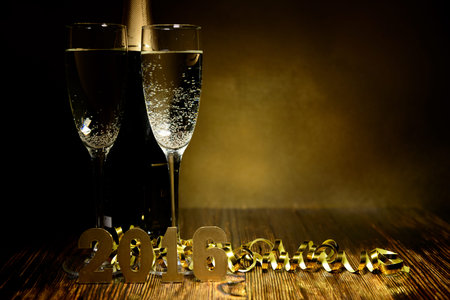 Two glasses of champagne and gold figures 2016 on a wooden background