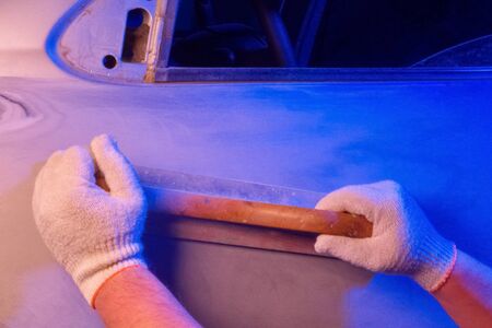 Car body repair, grinding parts with a hand tool in garage conditions, abstract blue lighting.の写真素材