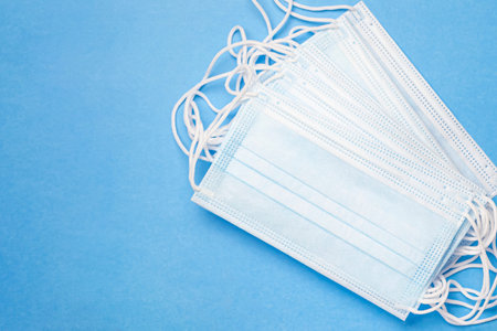Many protective medical masks on a blue background. The concept of epidemic, pandemic, virus.