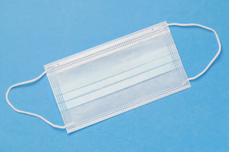 One protective medical mask on a blue background. The concept of epidemic, pandemic, virus.