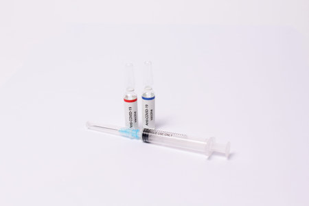 Two medicine ampule with anti covid-19 vaccine and syringe on white background