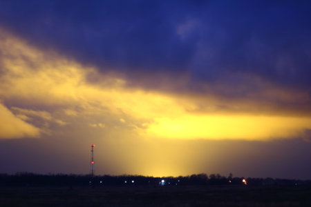 Light pollution by illuminated greenhouses at early morning. Glowing clouds. Cell phone tower on...