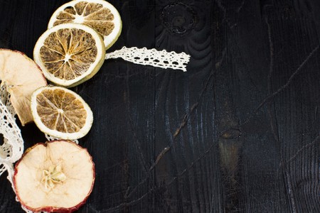 Slices of dried Apple and an orange lying on a black wood textureの写真素材