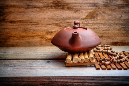 clay Chinese teapot on a wooden stand on an old boardの写真素材