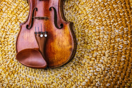 An old violin on a colored knitted rug of warm tonesの写真素材