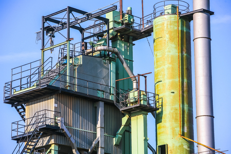 a fragment of some large refinery with a variety of technical designs, a fractionating column, a covered conveyor structure and burning lanternsの写真素材