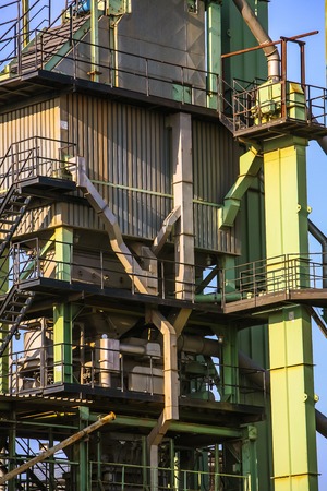 a fragment of some large refinery with a variety of technical designs, a fractionating column, a covered conveyor structure and burning lanternsの写真素材