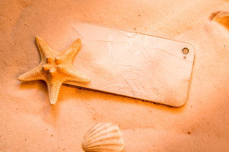 phone with a broken screen on the beach sand.の写真素材