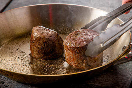 grilled beef steak with spieses on frying pan in a restaurantの写真素材
