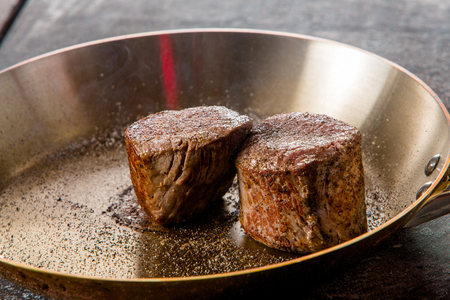 grilled beef steak with spieses on frying pan in a restaurantの写真素材