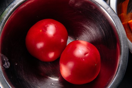 two fresh tomatoes in a iron salad bowlの写真素材