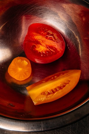 two fresh tomatoes in a iron salad bowlの写真素材
