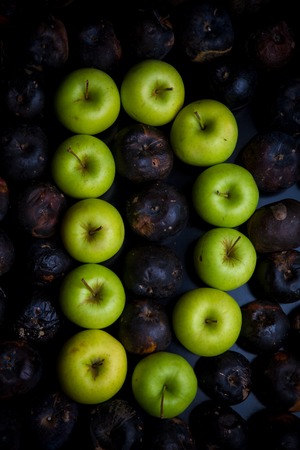 Fresh green apple alphabet letter on a background of rotten applesの写真素材