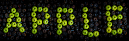 Fresh green apple alphabet letter on a background of rotten applesの写真素材