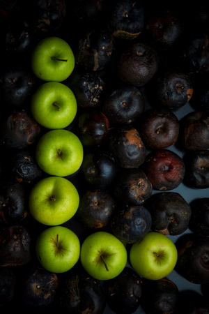 Fresh green apple alphabet letter on a background of rotten applesの写真素材