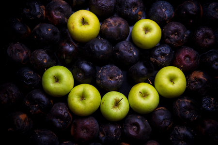 Fresh green apple alphabet letter on a background of rotten applesの写真素材