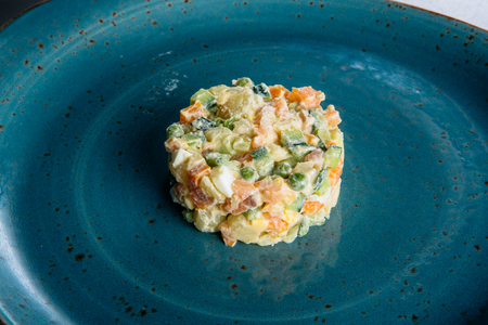 Russian salad on a blue plate with salmon and eggsの写真素材