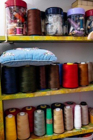 spools of colored thread in the workshop on the shelfの写真素材