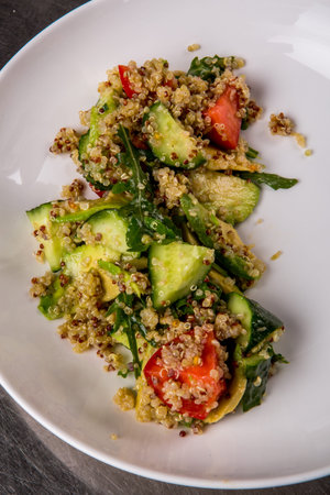 quinoa salad with tomato, cucumber, lemon and avocado on a white plateの写真素材