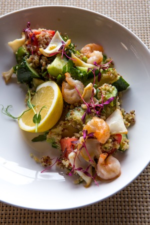 quinoa salad with tomato, cucumber, lemon and avocado on a white plateの写真素材