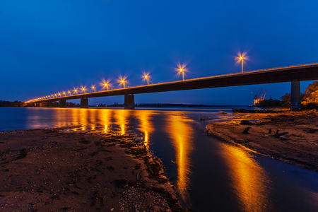 Steel bridge across river at night with artificial lightningの写真素材