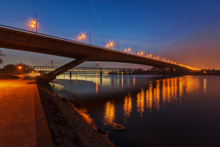 Steel bridge across river at night with artificial lightningの写真素材