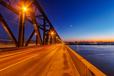 Steel bridge across river at nightの写真素材